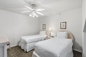 A hotel room with two single beds, a ceiling fan, a bedside table with a lamp, and two framed wall art pieces. - French Quarter Resort | 2BR + Loft | Sleeps 8 (Branson)