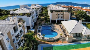 A resort with a swimming pool, multiple buildings, and a view of the sea. - Apt. in Beachfront Condominium w/ Pool Rvg2207 (Florianópolis)