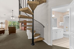 Ein modernes Interieur mit einer Wendeltreppe, einem Wohnzimmer mit Sofa und Lampe sowie einem Badezimmer mit Waschbecken und Toilette.