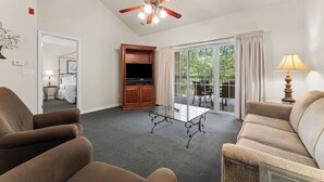 A hotel room with a ceiling fan, a television, a glass table, and seating. - Family Condo | 2 Kings, Loft | Great Location (Branson)