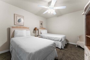 Ein Hotelzimmer mit zwei Betten, einem Deckenventilator und einem Stuhl.