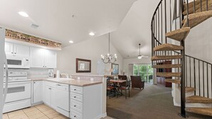 A modern kitchen with white cabinetry, a central island, and a dining area with a chandelier. - Spacious Family Condo | 2 Kings + Loft (Branson)