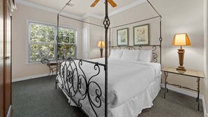 A four-poster bed with a canopy, a bedside table with a lamp, and two framed pictures on the wall. - French Quarter Resort | Family Condo Near Shows (Branson)