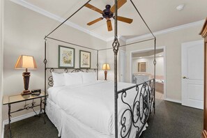 A four-poster bed with a ceiling fan, a bedside table with a lamp, and framed artwork on the wall. - French Quarter Resort | Family Condo Near Shows (Branson)