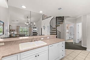 A modern kitchen with a central island, a chandelier, and a staircase leading to an upper level. - Near the Branson Strip | 2BR + Loft Condo (Branson)