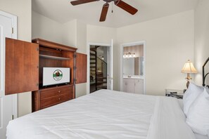 A bedroom with a bed, a wooden wardrobe, a bathroom with a mirror, and a ceiling fan. - Near the Branson Strip | 2BR + Loft Condo (Branson)