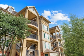 A multi-story residential building with balconies, a brick facade, and a clear blue sky. - Pool • Hot Tub • 2BR + Loft | Branson Resort (Branson)