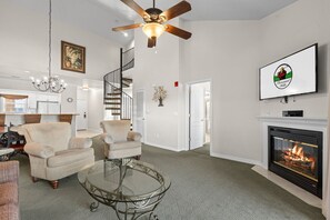 A living room with a fireplace, a ceiling fan, and a staircase. - Pool • Hot Tub • 2BR + Loft | Branson Resort (Branson)