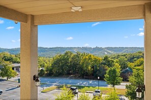 A covered outdoor area with a view of a parking lot, a street, and a hilly landscape. - Pool • Hot Tub • 2BR + Loft | Branson Resort (Branson)