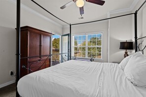 A bedroom with a four-poster bed, a wooden wardrobe, a window with blinds, and a ceiling fan. - French Quarter | 2 King Bedrooms + Loft (Branson)