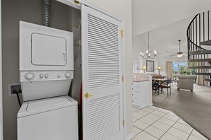 A laundry room with a front-loading washer and dryer, a sliding door closet, and a dining area with a chandelier and a view of the outdoors. - French Quarter | 2 King Bedrooms + Loft (Branson)
