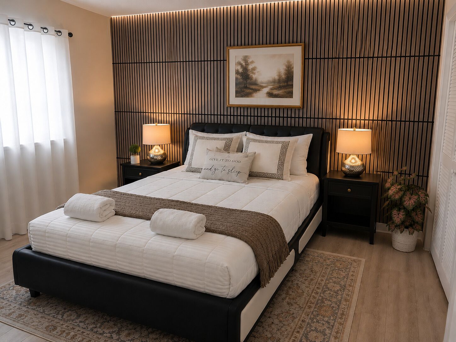 A modern bedroom with a large bed, two bedside tables with lamps, a framed picture on the wall, and a patterned rug.