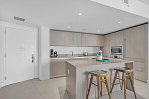 Una cocina moderna con una isla central, taburetes de madera y electrodomésticos integrados.