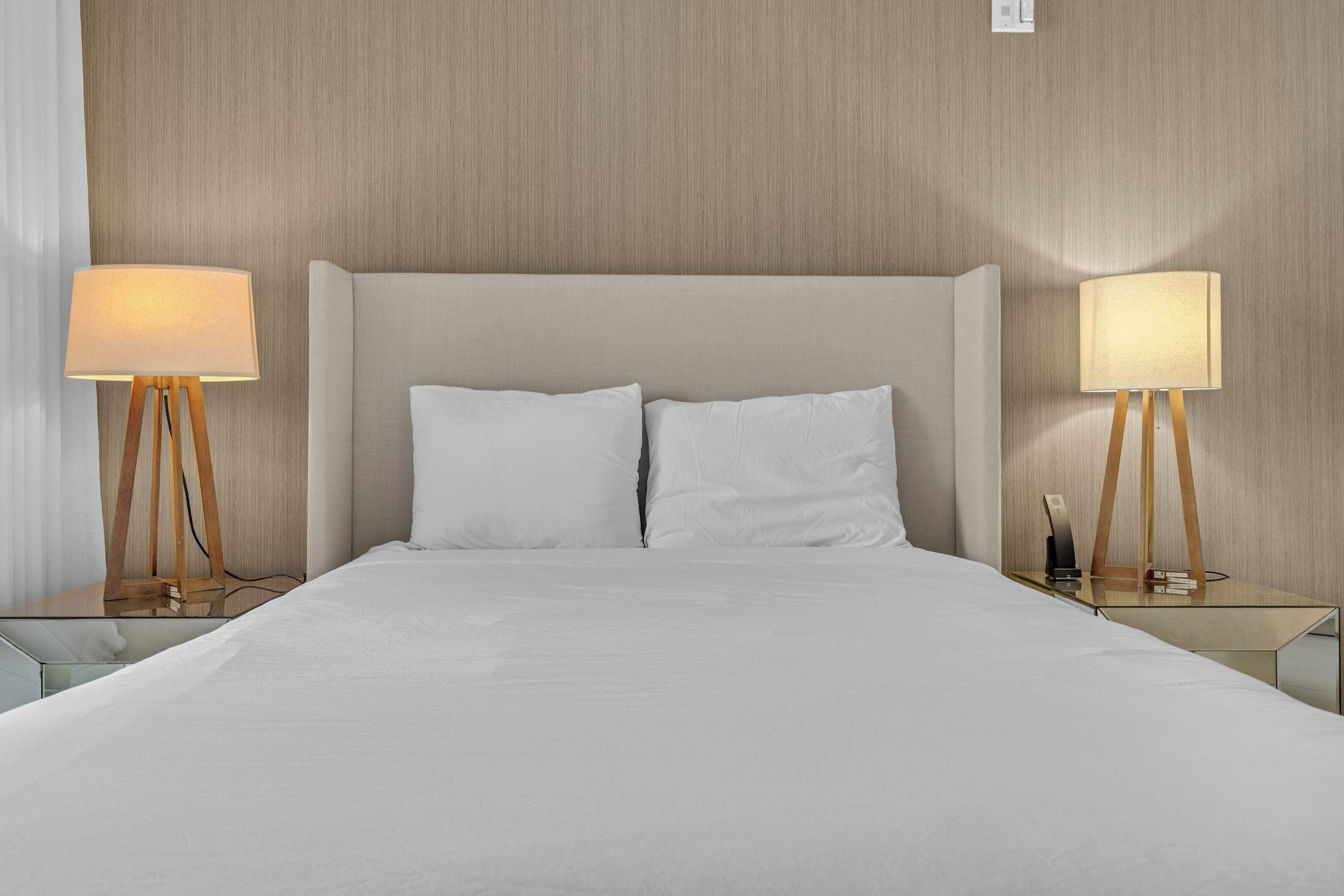 Ein Hotelzimmer mit einem großen Bett, zwei Nachttischen inklusive Lampen und einem Holzkopfteil.