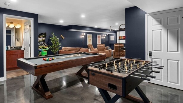 Ett rum med ett biljardbord, ett fotbollsspel och en soffa.