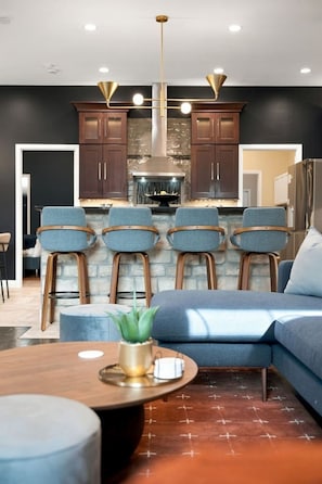A modern kitchen with dark cabinetry, a central island, and bar stools. - Soulard Sensational|Sleeps18|HotTub|PuttPutt|Games (St. Louis)
