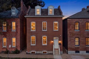 A two-story brick building with multiple windows, a front door, and a small porch area.