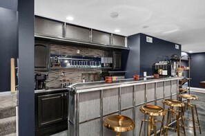 A modern kitchen with a bar area, stainless steel appliances, and bar stools.