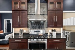 A modern kitchen with dark wood cabinets, a stainless steel range hood, and a built-in oven. - Soulard Sensational|Sleeps18|HotTub|PuttPutt|Games (St. Louis)