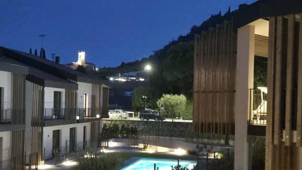 Ein Innenhof mit Swimmingpool, ein Gebäude mit Balkon und ein weiter Turm in der Ferne.