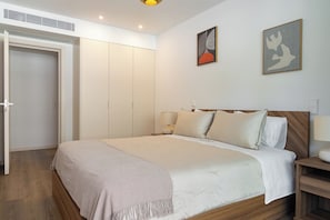 Ein Schlafzimmer mit einem Bett, Nachttischen, einem Kleiderschrank und zwei an der Wand hängenden Bildern.