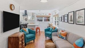 Una sala de estar con sillones color turquesa, un sofá y un mueble de madera.