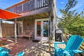 Ett trädäck med ett takförsett sittområde, en täckt entré och en blå Adirondack-stol.