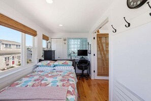 Ein Schlafzimmer mit einem Bett, einem Schreibtisch, einem Sessel, einem Fernseher und einem Fenster.