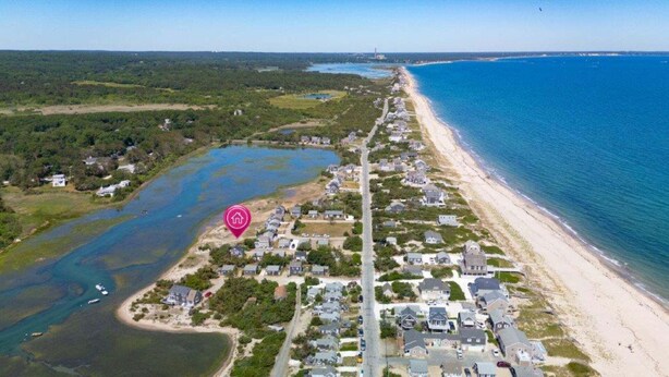 Vista aérea de una zona residencial costera con casas, una playa y una masa de agua.
