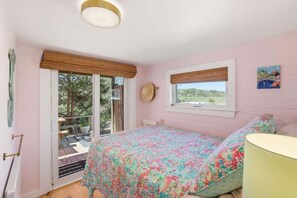 Une chambre avec un lit, une fenêtre donnant sur un paysage agréable et une porte menant à un espace extérieur.