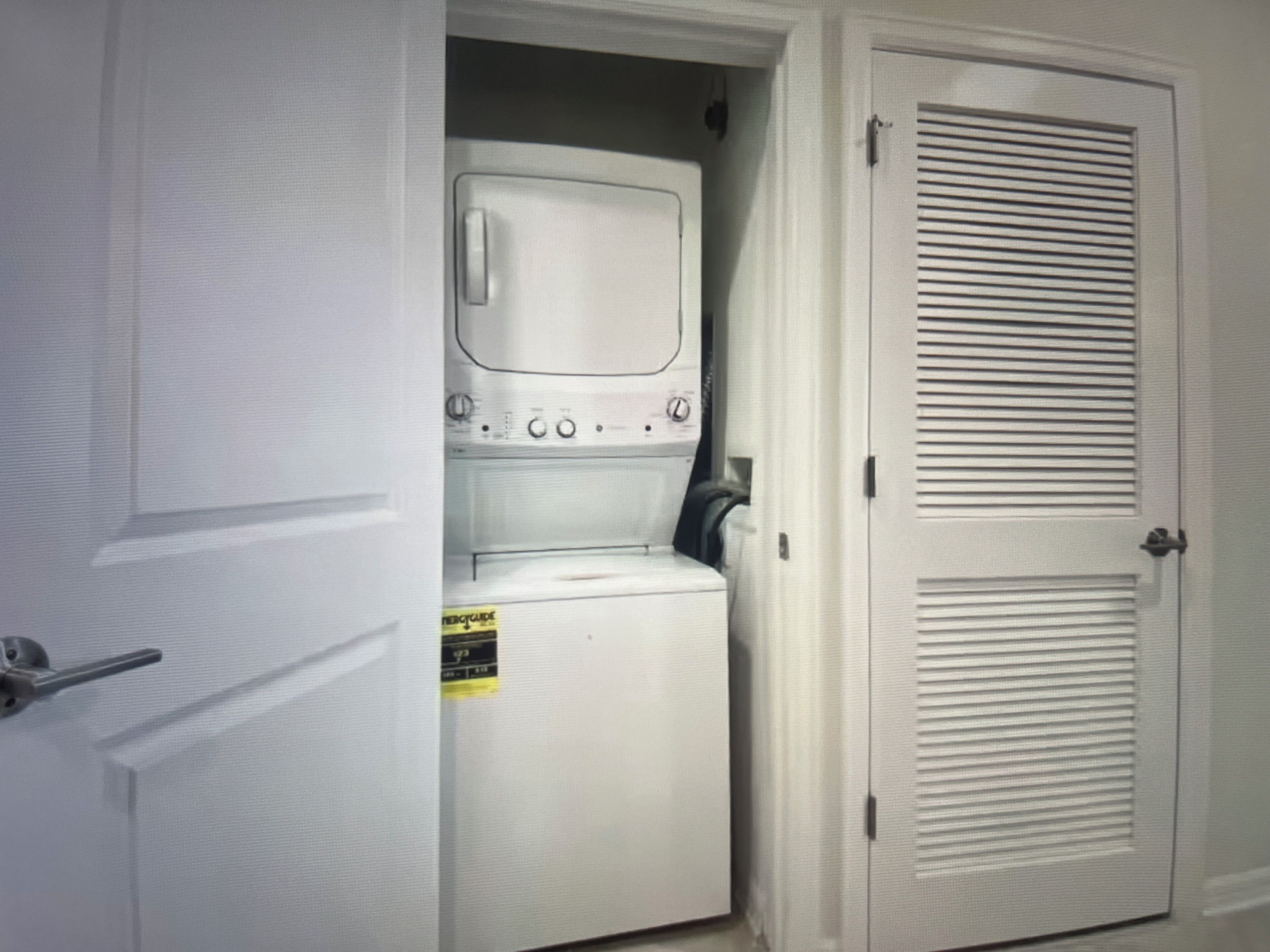 A laundry area with a washing machine and dryer, a door with a handle, and a wall-mounted vent.