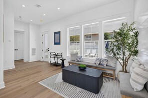 Un salon moderne comprenant un canapé, une table basse et un coin repas avec des chaises.