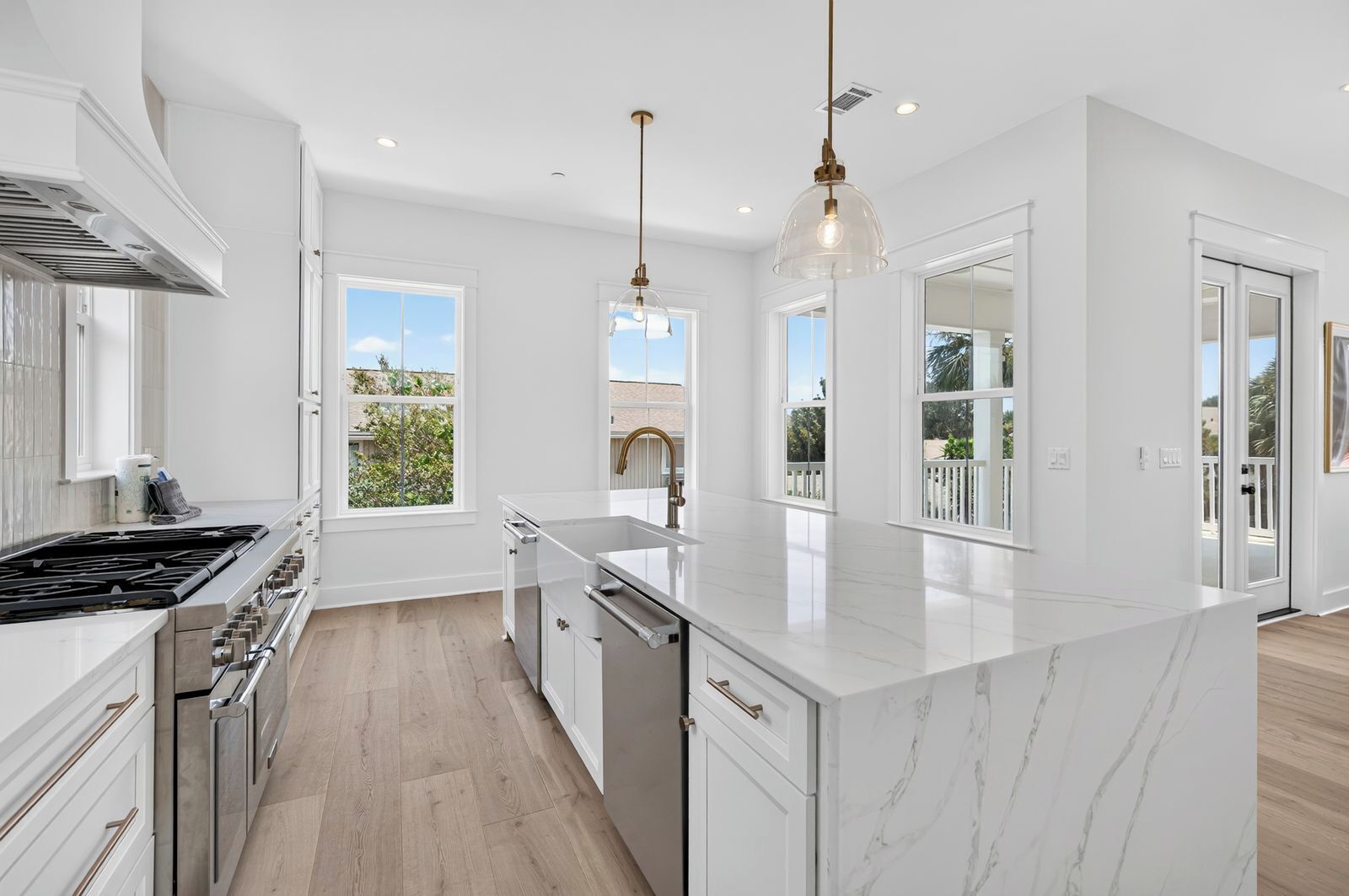 A modern kitchen with white cabinetry, a large island, and a view of the outdoors.