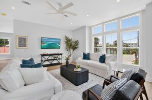 Ein großzügiges Wohnzimmer mit einem weißen Sofa, einem schwarzen Couchtisch und einem großen Fenster mit Blick ins Freie.