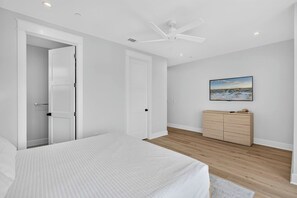 Ein Schlafzimmer mit einem Bett, einem Kleiderschrank, einem Deckenventilator und einem Bild an der Wand.