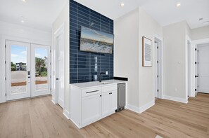 A modern kitchen with white cabinetry, a blue backsplash, and a large window. - Serenity Shores: Private Beach, Ocean Views, Heated Pool, Golf Cart, Game Room (Miramar Beach)