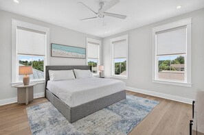 A bedroom with a bed, two bedside tables, a ceiling fan, and large windows. - Serenity Shores: Private Beach, Ocean Views, Heated Pool, Golf Cart, Game Room (Miramar Beach)