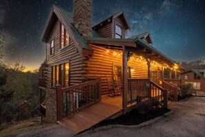Eine Blockhütte mit Veranda, Schornstein und Lichterkette.
