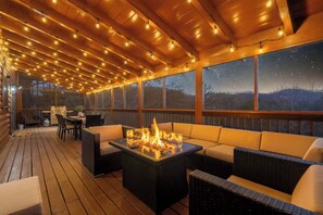 Una terraza al aire libre con una chimenea, asientos y vistas al cielo nocturno.