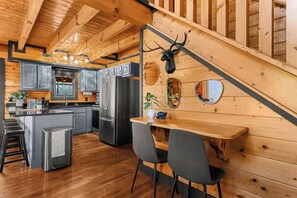 Cocina moderna con una isla central, armarios grises y un refrigerador de acero inoxidable.