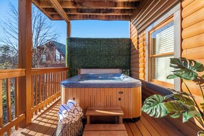 Una terraza de madera con un jacuzzi, una banca de madera y una planta en maceta.