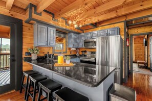 Una cocina moderna con armarios grises, electrodomésticos de acero inoxidable y una isla central con taburetes de bar.