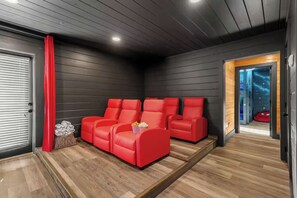 A room with a dark wooden ceiling, a red curtain, and a seating area with red chairs. - Luxe Themed Cabin | Theater | Hot Tub | Mtn Views | Sleeps 18+ (Pigeon Forge)