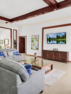A living room with a sofa, coffee table, TV, and a herringbone-patterned cabinet. - Spacious 12 Bedrooms Villa for Large Groups in St Ann, Jamaica (Saint Ann's Bay)