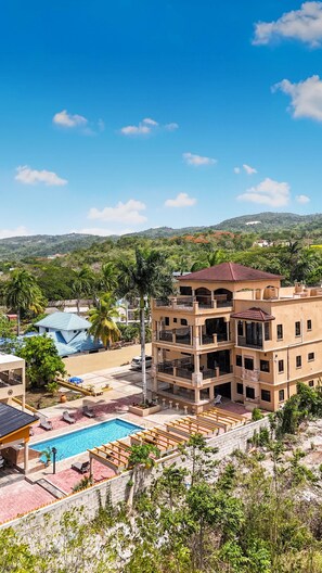 A multi-story building with a pool and outdoor seating, surrounded by greenery and hills. - Spacious 12 Bedrooms Villa for Large Groups in St Ann, Jamaica (Saint Ann's Bay)
