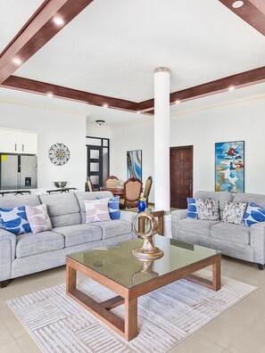 A spacious living room with two grey sofas, a glass coffee table, and a white rug. - Spacious 12 Bedrooms Villa for Large Groups in St Ann, Jamaica (Saint Ann's Bay)