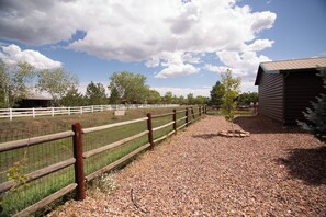 A fenced outdoor area with gravel paths, wooden fences, and a building with a sloped roof.