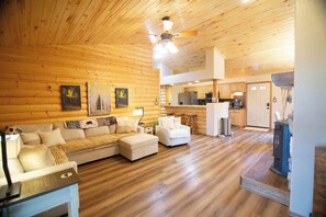 A log cabin interior with a living area, kitchen, and dining space.