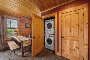 A laundry room with wooden walls and doors, a washing machine, and a table with a lamp. - Lazy Daze: Views, Pet Friendly, Outdoor Pavilion (Banner Elk)