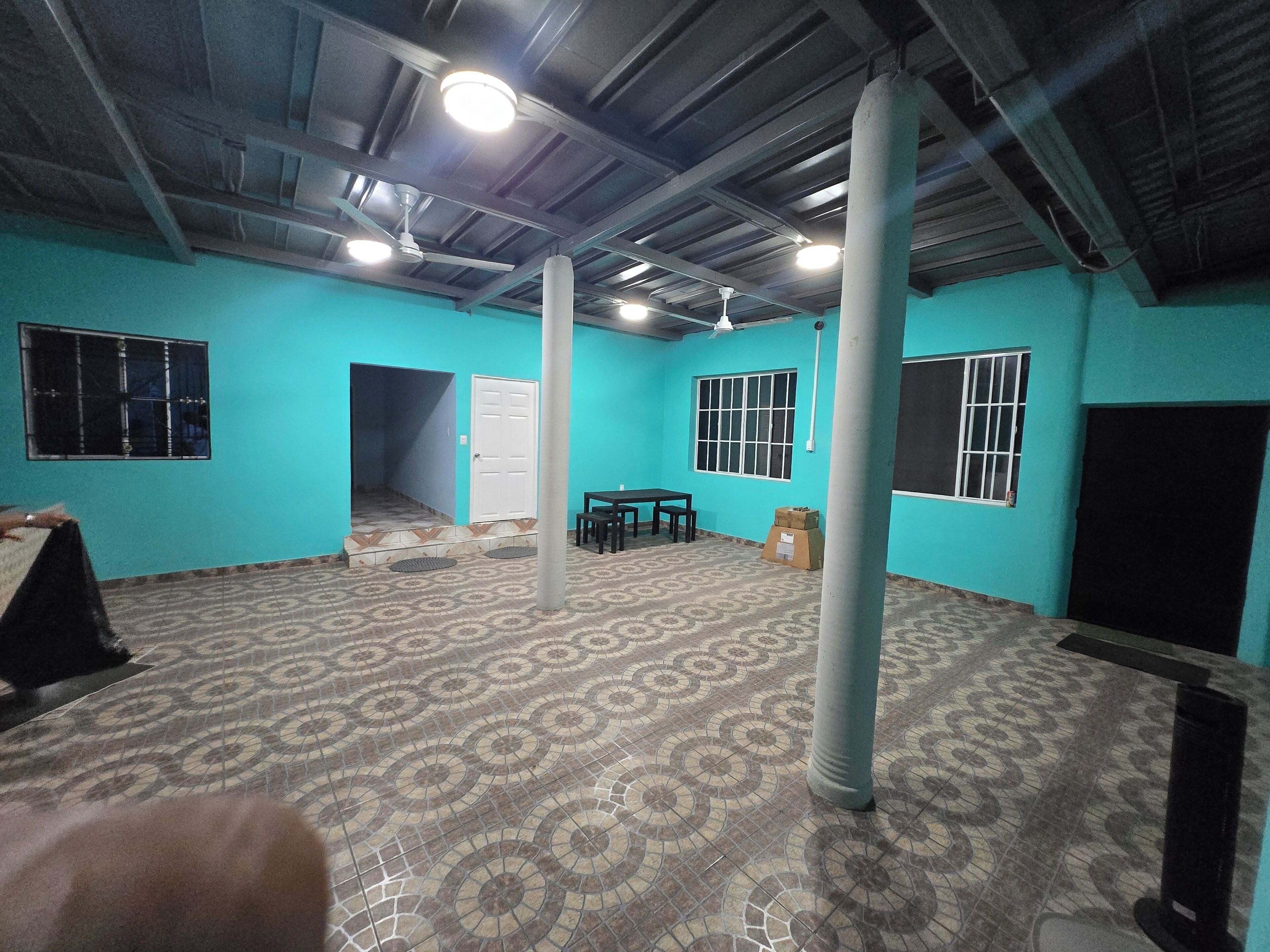 A room with teal walls, a patterned floor, a ceiling fan, and a table with chairs.